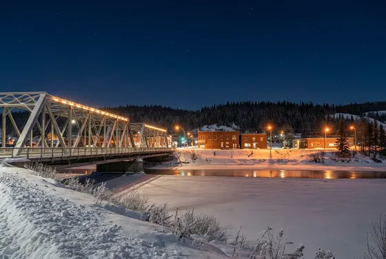 Steel truss bridge over a frozen river at night